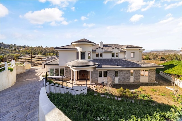 view of front of house with stone siding, fence, and stucco siding