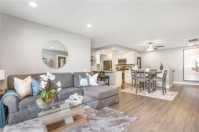 living area featuring recessed lighting, visible vents, light wood-style flooring, a ceiling fan, and baseboards