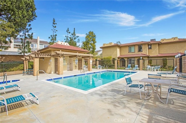 community pool with a patio area and fence