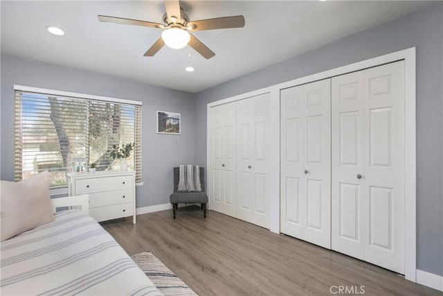 bedroom with a ceiling fan, wood finished floors, baseboards, and two closets