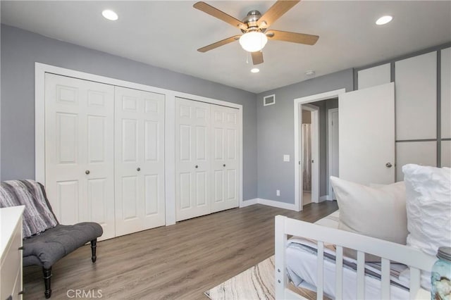 bedroom featuring multiple closets, recessed lighting, visible vents, and wood finished floors