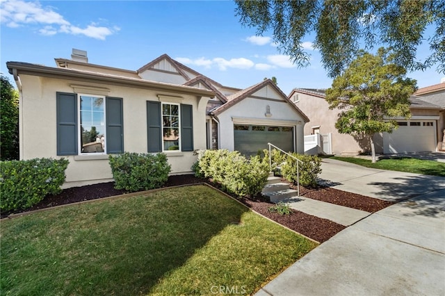 english style home with a front yard, driveway, an attached garage, and stucco siding