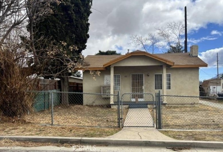 view of front of property featuring a gate, fence, and stucco siding