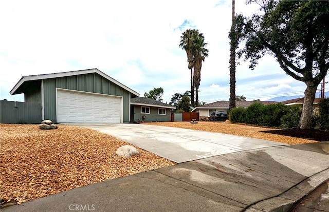 ranch-style home featuring a garage, concrete driveway, and fence