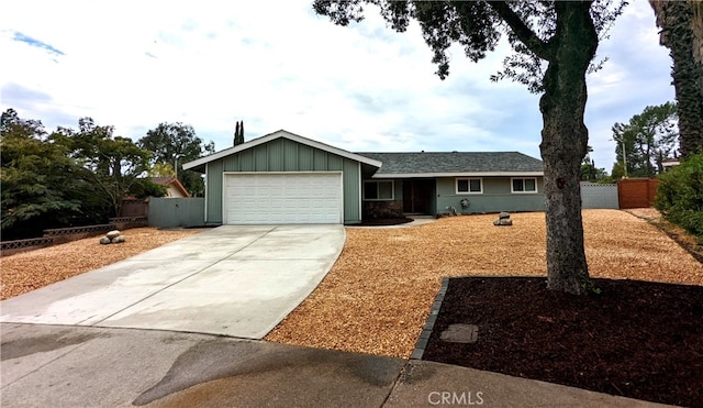 ranch-style home featuring board and batten siding, fence, driveway, and an attached garage