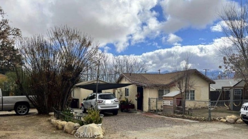 view of front of house with a carport, a fenced front yard, and gravel driveway