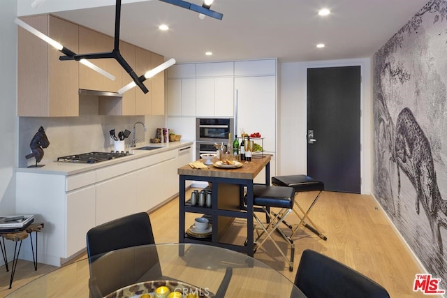 kitchen with light countertops, light wood-style floors, white cabinetry, a sink, and modern cabinets