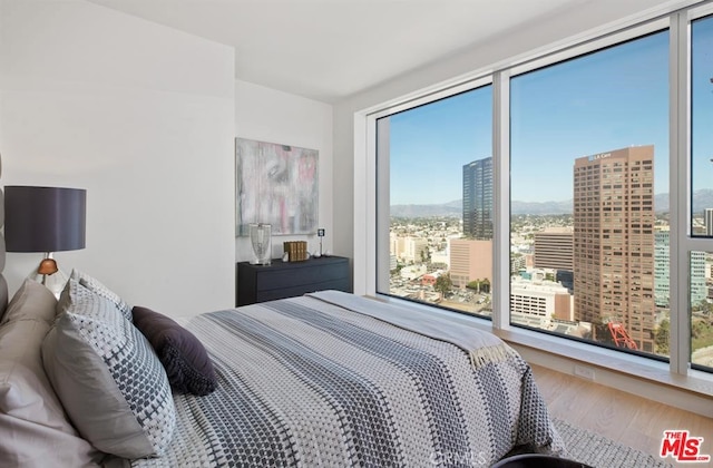 bedroom featuring a view of city and wood finished floors