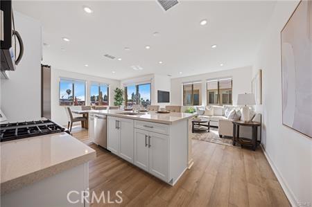 kitchen with light countertops, appliances with stainless steel finishes, light wood-style floors, open floor plan, and white cabinetry