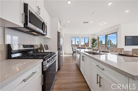 kitchen featuring white cabinets, appliances with stainless steel finishes, wood finished floors, a sink, and recessed lighting