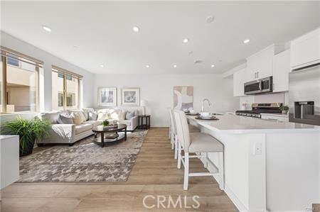 kitchen with stainless steel appliances, a sink, white cabinets, light countertops, and light wood-type flooring