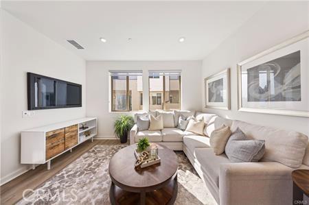 living room with baseboards, visible vents, and wood finished floors