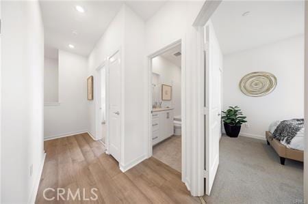 corridor featuring recessed lighting, light wood-type flooring, and baseboards