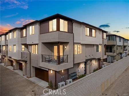 rear view of house featuring an attached garage, fence, a residential view, and stucco siding