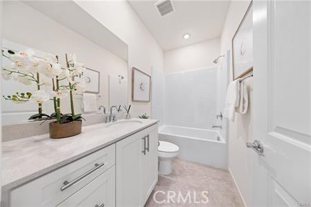 bathroom featuring bathing tub / shower combination, visible vents, toilet, vanity, and tile patterned flooring