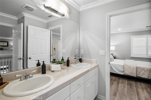 bathroom with ornamental molding, visible vents, a sink, and wood finished floors