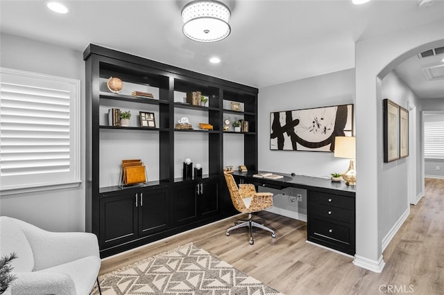 office space featuring baseboards, built in desk, visible vents, and light wood-style floors