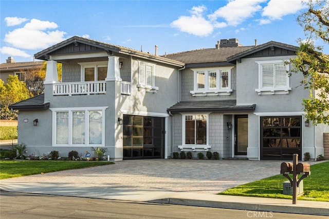 view of front of home featuring an attached garage, a balcony, decorative driveway, stucco siding, and a chimney