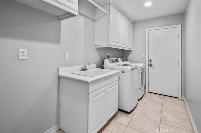 laundry room featuring washing machine and clothes dryer, light tile patterned floors, cabinet space, a sink, and baseboards