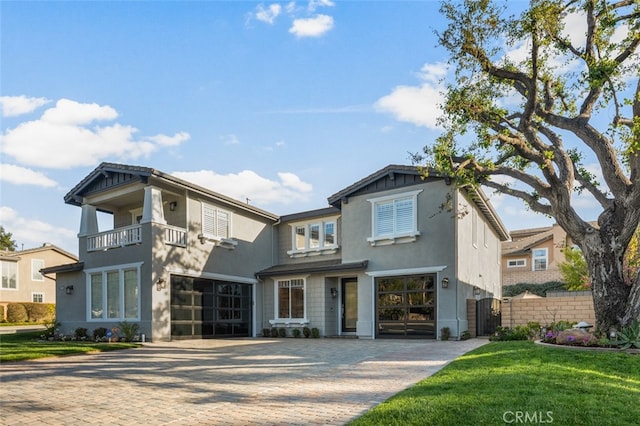 view of front of house with a balcony, decorative driveway, and stucco siding