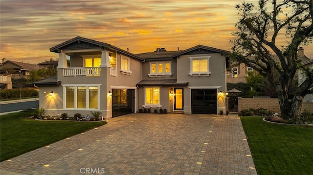 view of front of house with a balcony, a front yard, a garage, and stucco siding