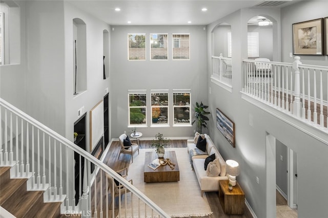 living room featuring stairway, recessed lighting, a towering ceiling, and baseboards