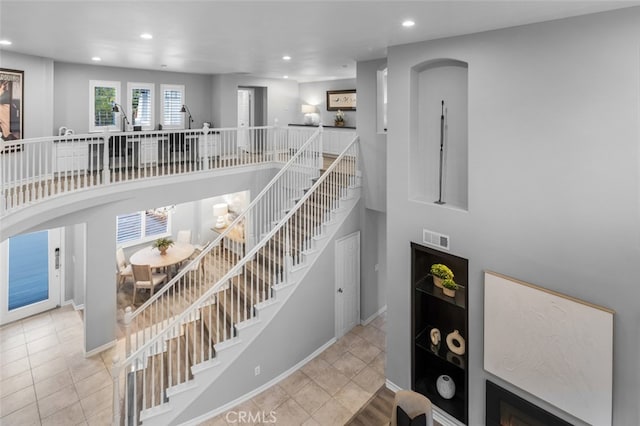 stairway with recessed lighting, visible vents, arched walkways, and a high ceiling