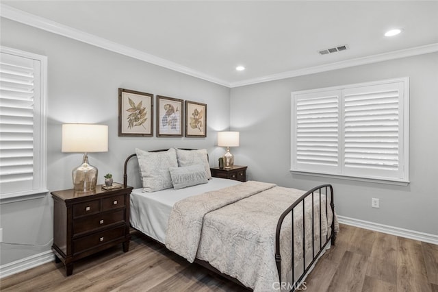 bedroom featuring baseboards, crown molding, visible vents, and wood finished floors