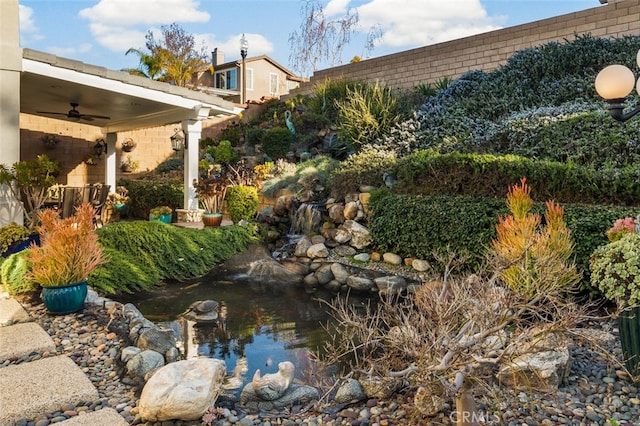 view of yard featuring a ceiling fan and a garden pond