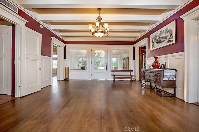 interior space featuring a wainscoted wall, beamed ceiling, wood finished floors, a chandelier, and a decorative wall