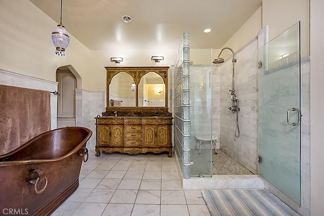 full bathroom with double vanity, a stall shower, visible vents, a soaking tub, and tile walls