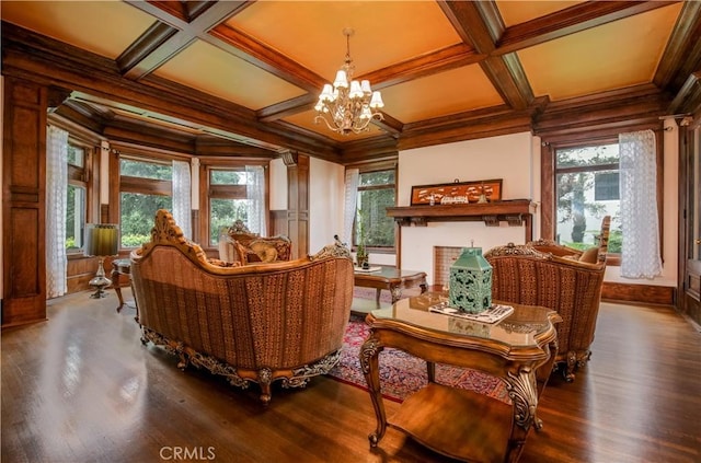 living area featuring a chandelier, coffered ceiling, crown molding, and wood finished floors