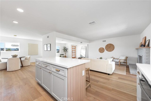 kitchen with light wood-style floors, visible vents, open floor plan, and light countertops