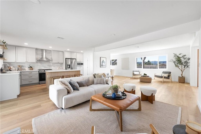 living room featuring recessed lighting, light wood-style flooring, baseboards, and visible vents