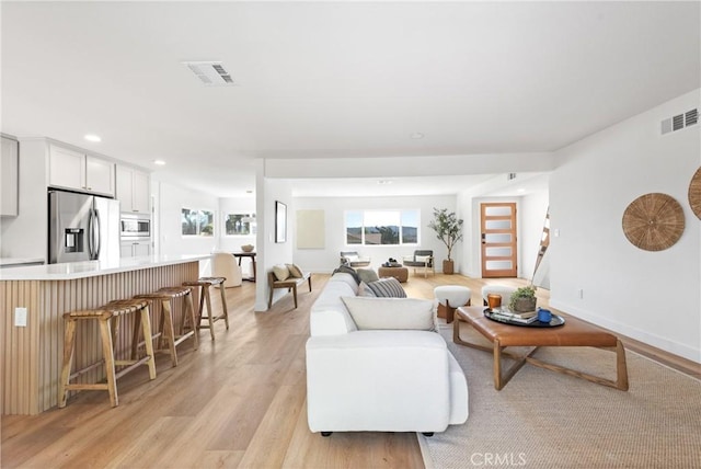 living area featuring light wood-type flooring, visible vents, baseboards, and recessed lighting