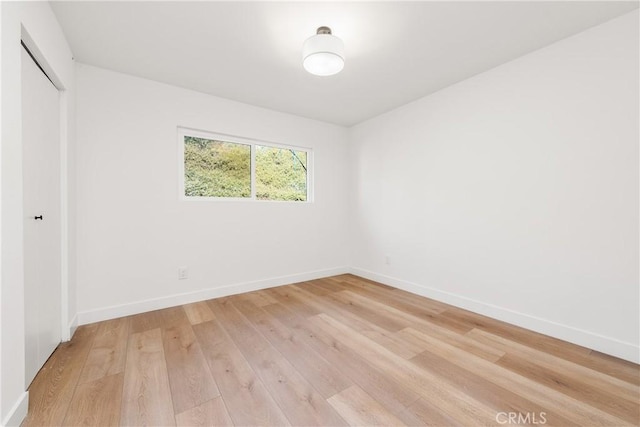 unfurnished room with baseboards and light wood finished floors