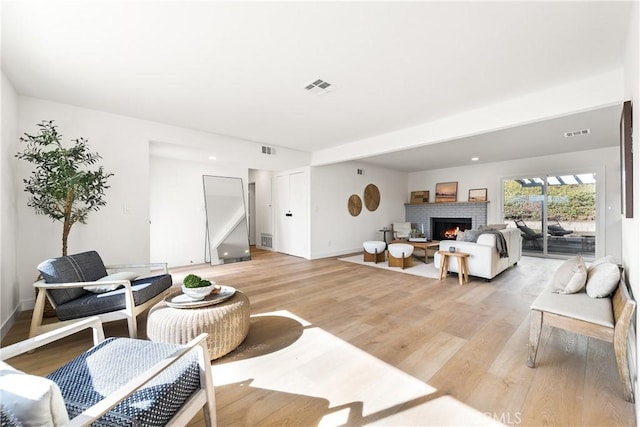 living room featuring a fireplace, visible vents, and light wood finished floors