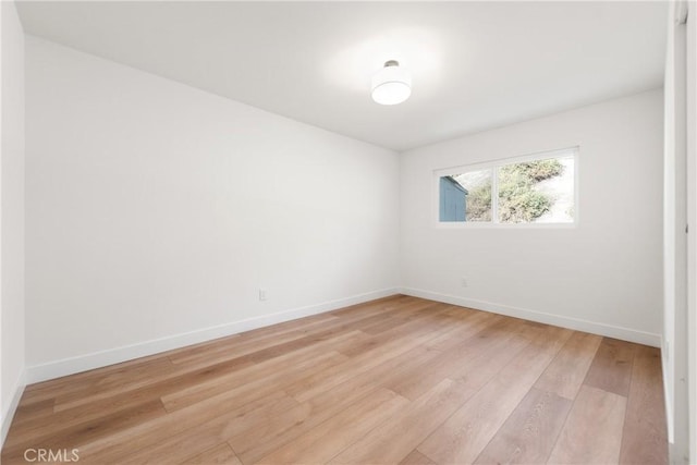 empty room featuring baseboards and light wood-style flooring