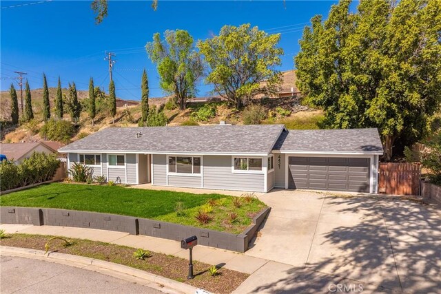 ranch-style house featuring a front yard, fence, a garage, and driveway