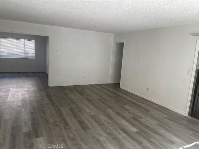 spare room with a textured ceiling, dark wood finished floors, and baseboards