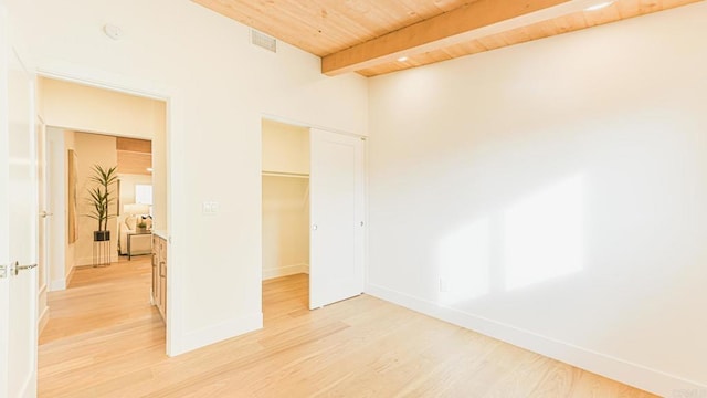 unfurnished room featuring visible vents, baseboards, wooden ceiling, light wood-style flooring, and beam ceiling