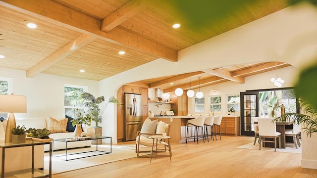 living area featuring arched walkways, wooden ceiling, light wood-style flooring, and vaulted ceiling with beams