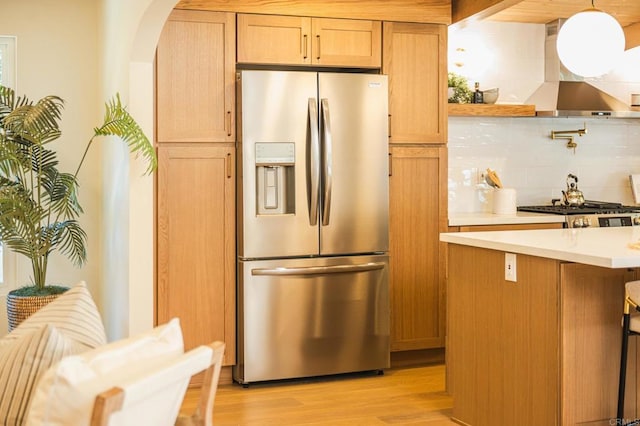 kitchen featuring arched walkways, stainless steel fridge with ice dispenser, light wood-style flooring, light countertops, and backsplash