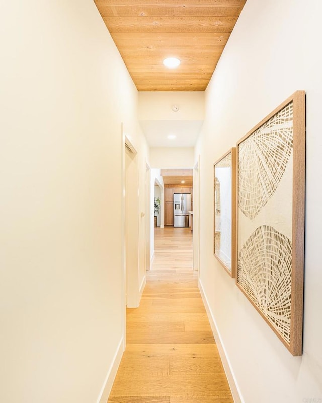 corridor featuring light wood finished floors, wooden ceiling, recessed lighting, and baseboards