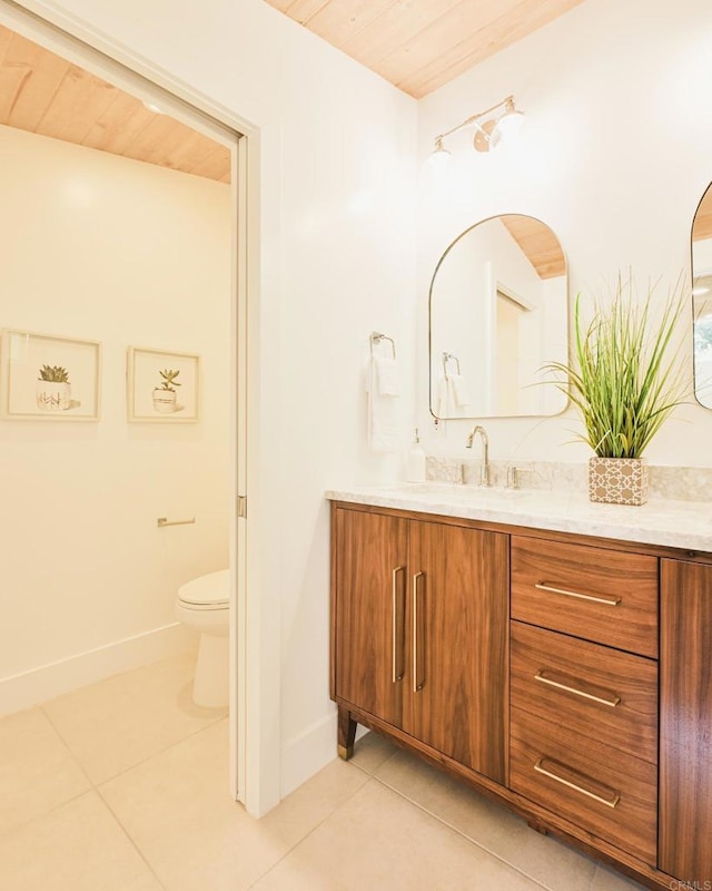 bathroom with toilet, tile patterned flooring, baseboards, and vanity