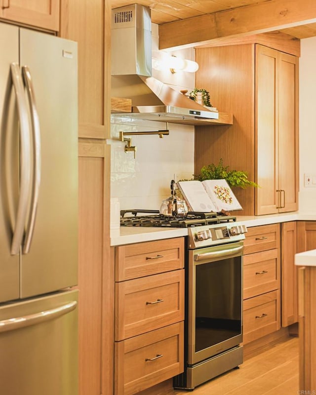 kitchen with appliances with stainless steel finishes, light countertops, light wood finished floors, and wall chimney exhaust hood