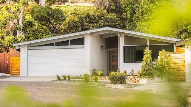 exterior space featuring a garage, fence, and stucco siding