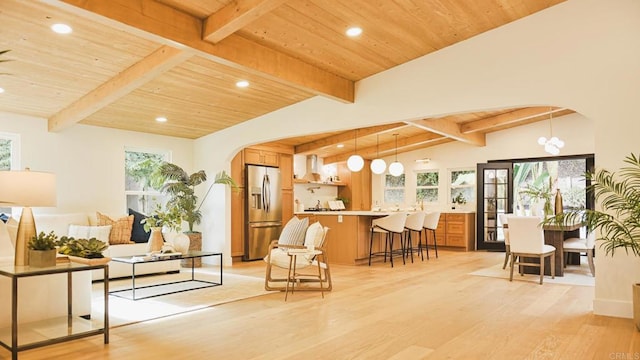 sitting room with vaulted ceiling with beams, wood ceiling, arched walkways, and light wood-style flooring