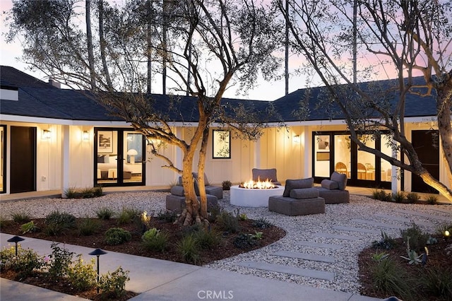 back of house at dusk with board and batten siding and an outdoor fire pit