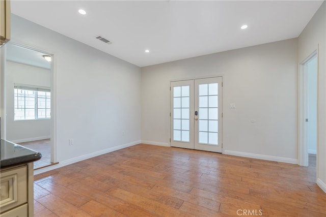 spare room with light wood finished floors, french doors, and recessed lighting